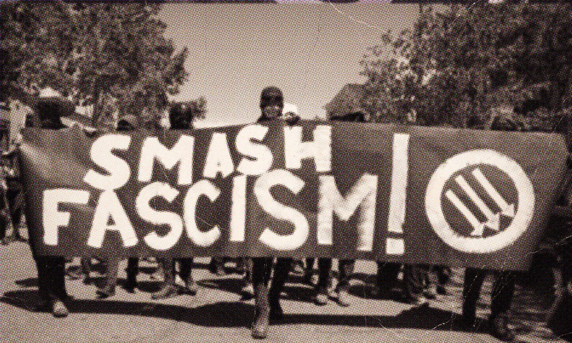 image of protester holding a sign that says smash fascism